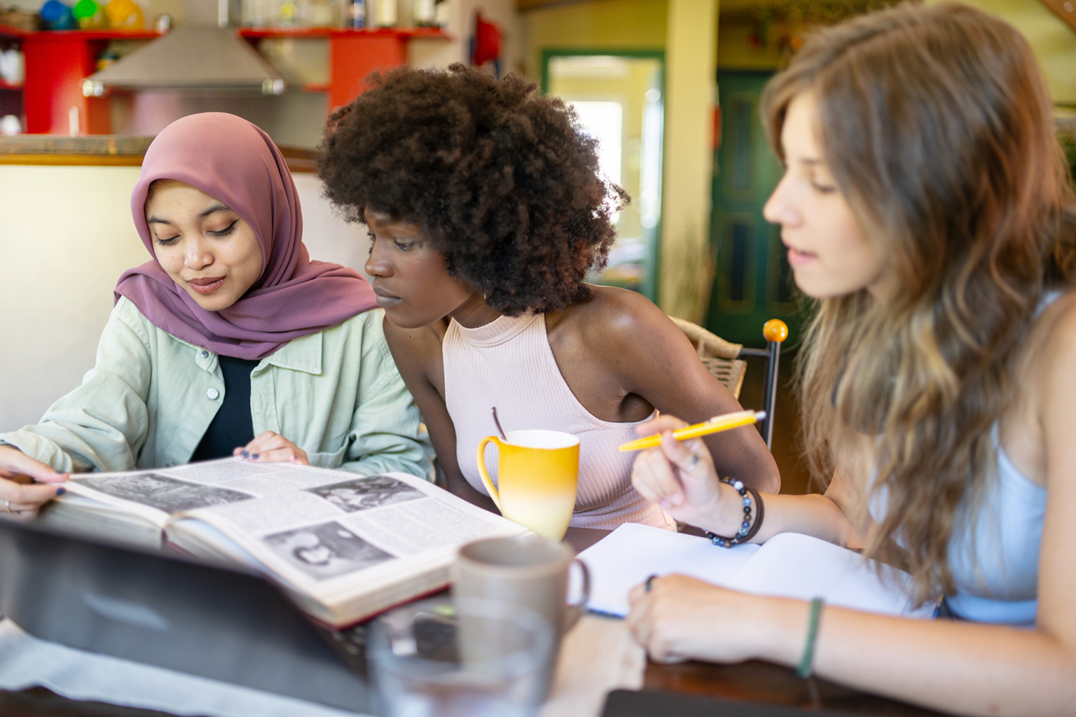 Three students studying together, sharing ideas and notes.