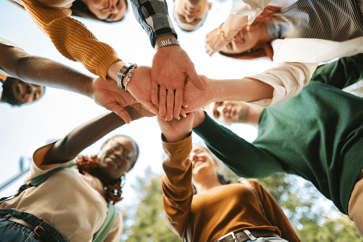 Group of diverse people joining hands in a circle, symbolizing unity and teamwork.