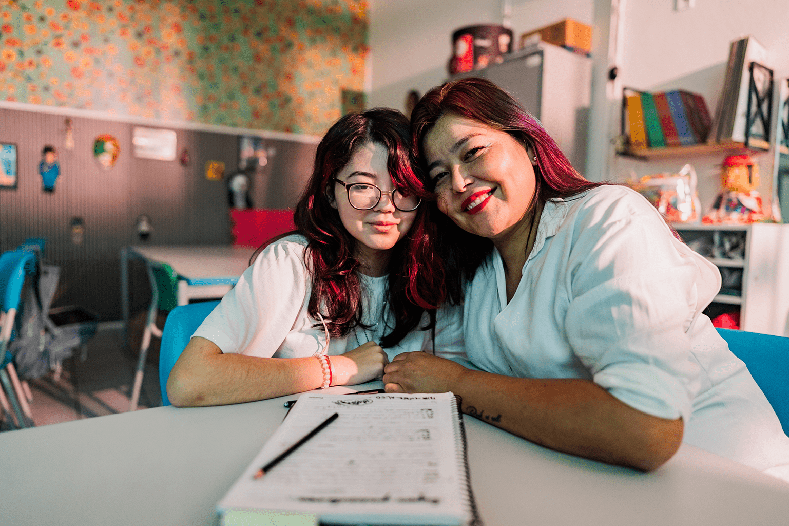 Two smiling women sitting closely with a menu in a cozy café.
