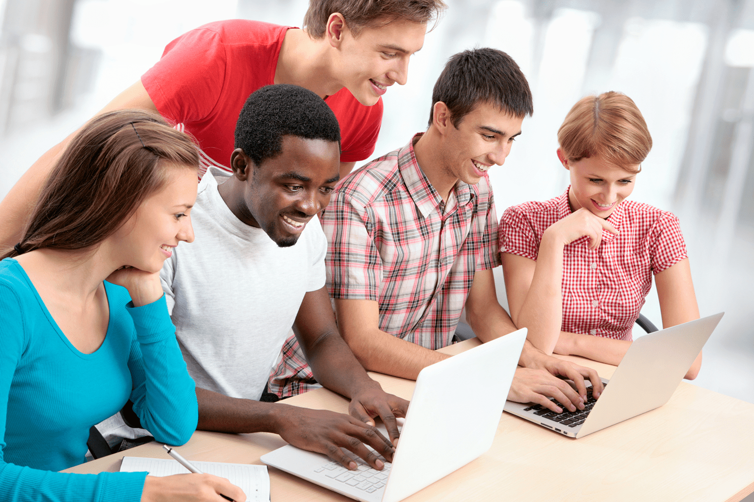 A diverse group of young adults collaborating around a laptop.