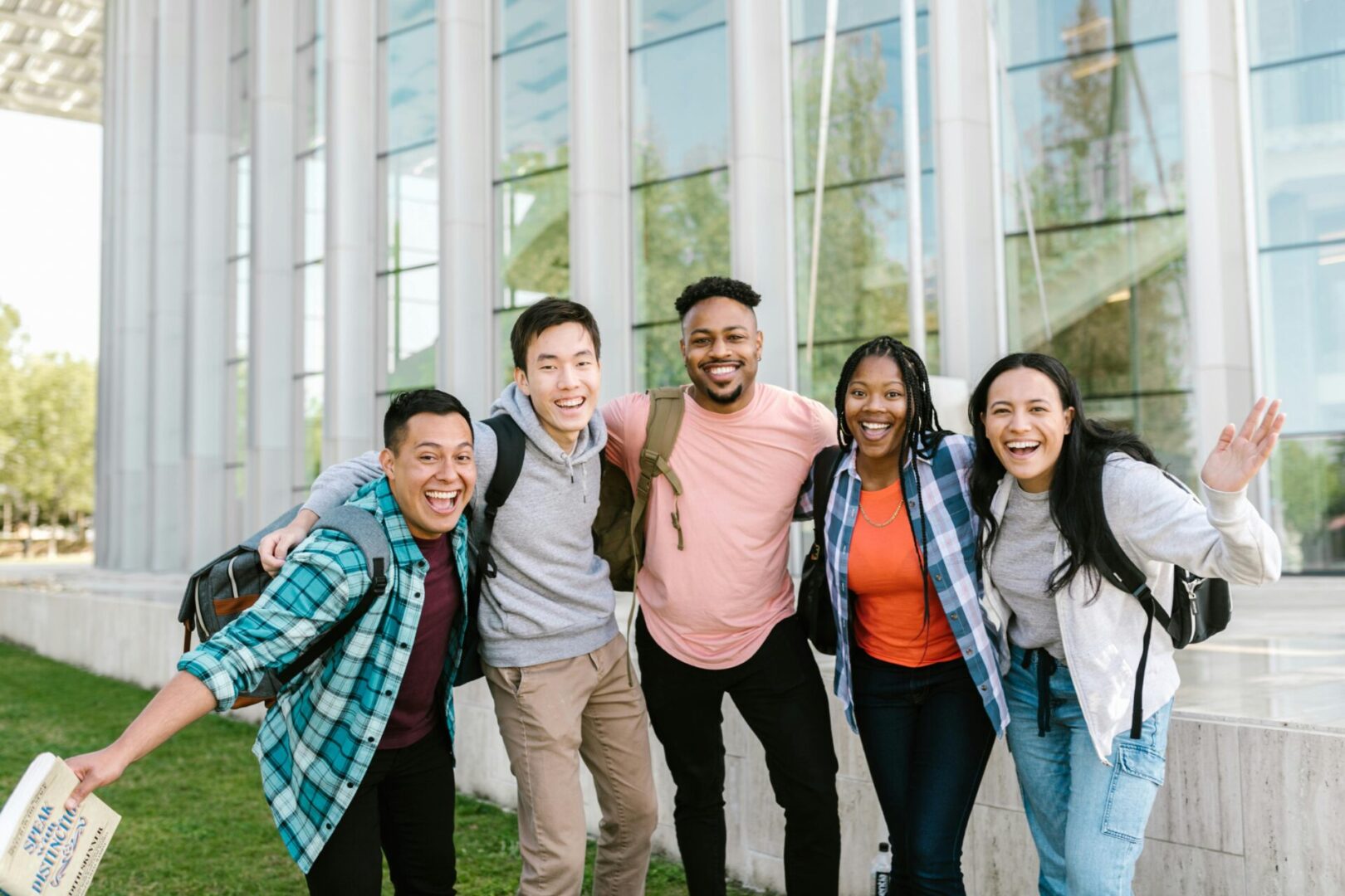 A diverse group of young adults smiling and posing outside a modern building.