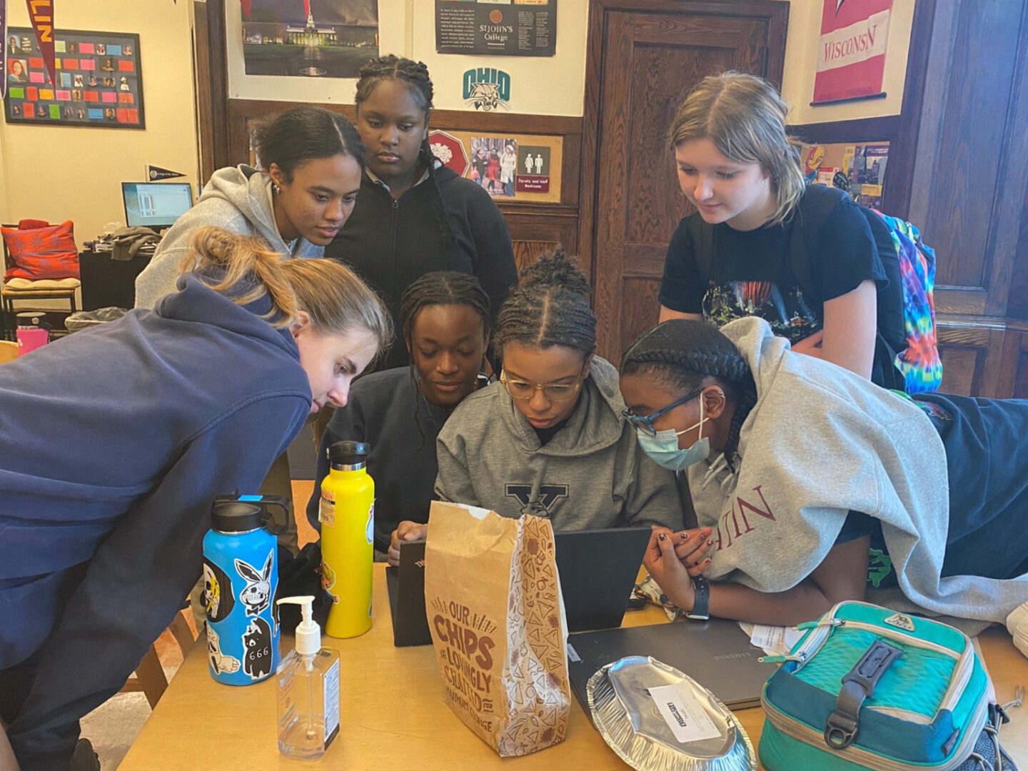 A group of students intently studying a tablet together in a classroom.